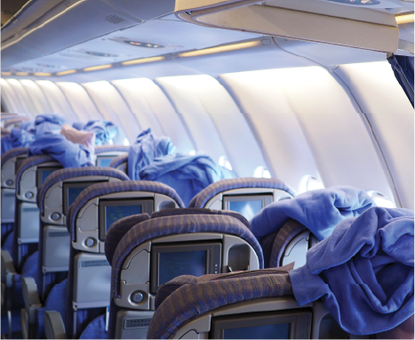 Airline interior showing modern seats with luxury blankets and other service items.